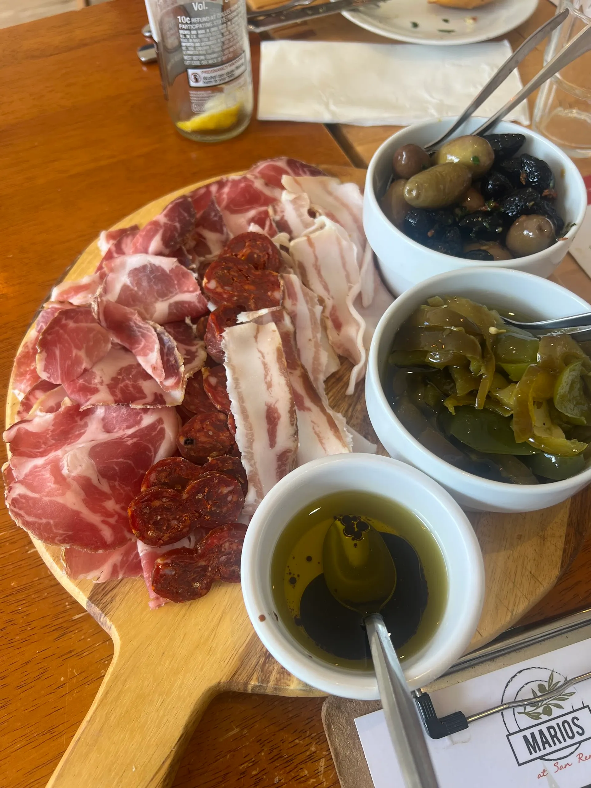 Charcuterie board with prosciutto, salami and cured meats alongside olives and pickled condiments