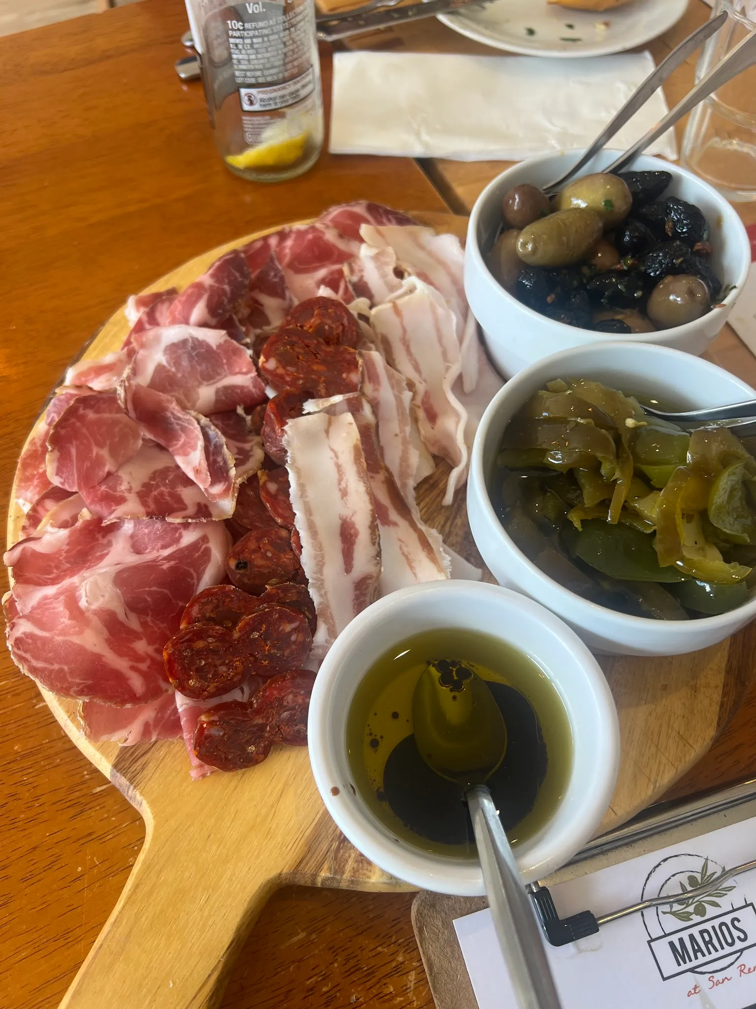 Charcuterie board with prosciutto, salami and cured meats alongside olives and pickled condiments