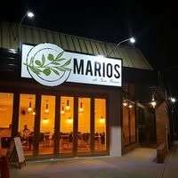 Mario's at San Remo restaurant facade at night with warm golden glow from interior lighting and illuminated signage